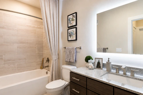 Bathroom with a tub shower, tile surround, and granite countertop at The Mayfair Apartments
