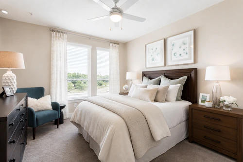 Bedroom with wide windows, carpet, and an accent chair in a Mayfair apartment home