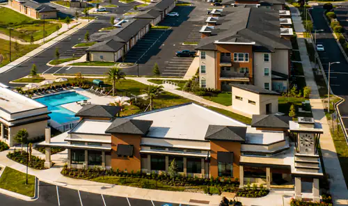 Aerial view of the pool deck, parking, and clubhouse at The Mayfair Apartments