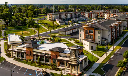 Aerial view of The Mayfair Apartments clubhouse, pool, and apartment buildings in Gainesville