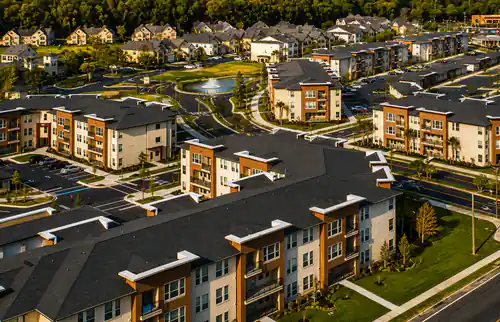Aerial view of The Mayfair Apartments buildings, pond, and landscaped grounds in Gainesville